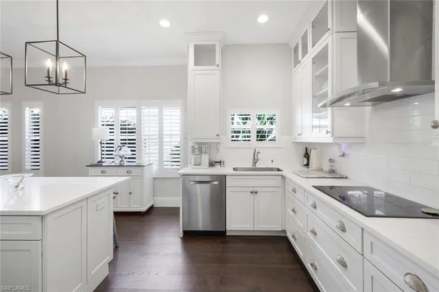 a large white kitchen with stainless steel appliances granite countertop a sink and dishwasher a stove with wooden floor