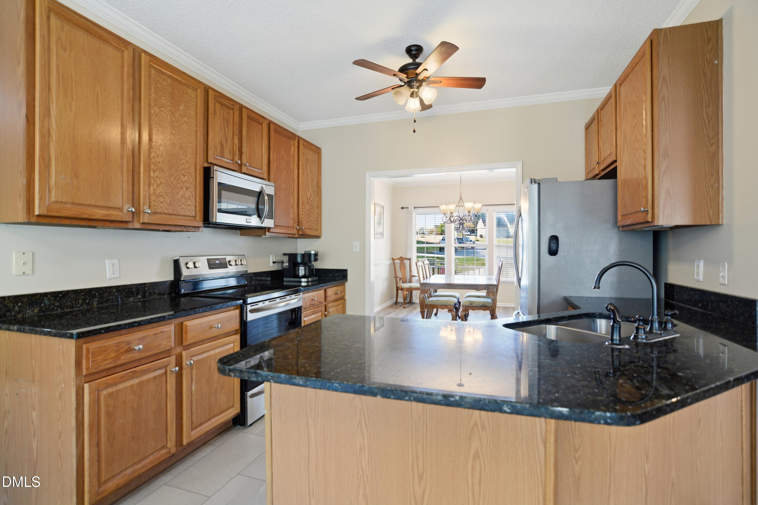 4801 Topstone Road Raleigh, NC 27603 - Photo 8 of 29 a kitchen with stainless steel appliances granite countertop a sink a stove top oven a dining table and chairs with wooden floor