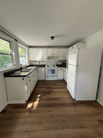 a kitchen with wooden floors and white appliances