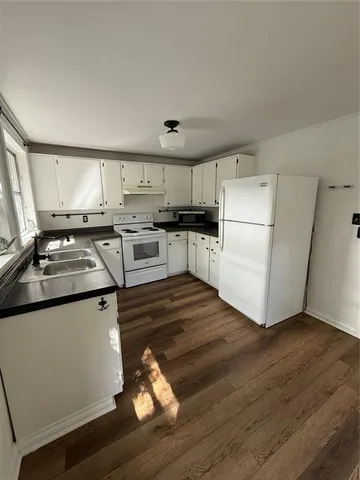 a kitchen with wooden floors and white appliances