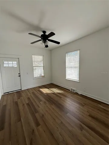 an empty room with wooden floor and windows