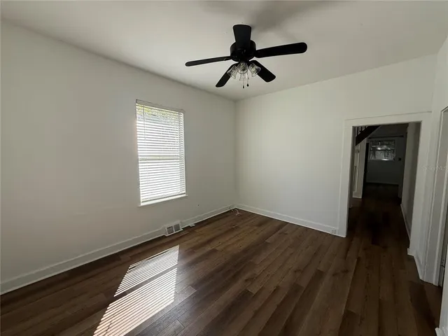 a view of empty room with wooden floor and fan