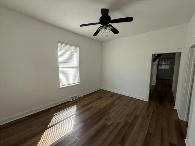 a view of empty room with wooden floor and fan