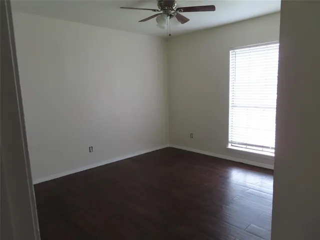 an empty room with wooden floor fan and windows