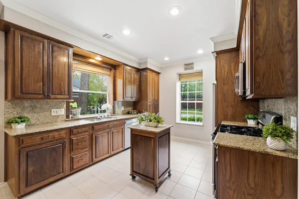 a kitchen with stainless steel appliances granite countertop a stove top oven a sink dishwasher a dining table and chairs with wooden floor