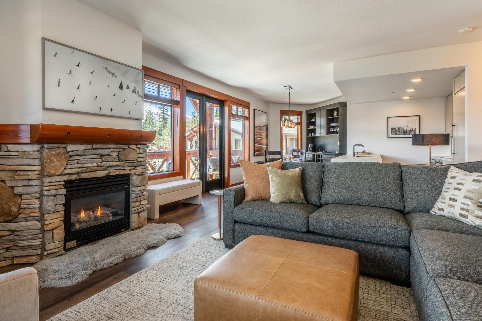 6201 Minaret Road, Unit 2430 Mammoth Lakes, CA 93546 - Photo 12 of 54 Living area featuring a stacked stone fireplace with a wood mantle, wood-finish flooring, and large windows with outdoor access