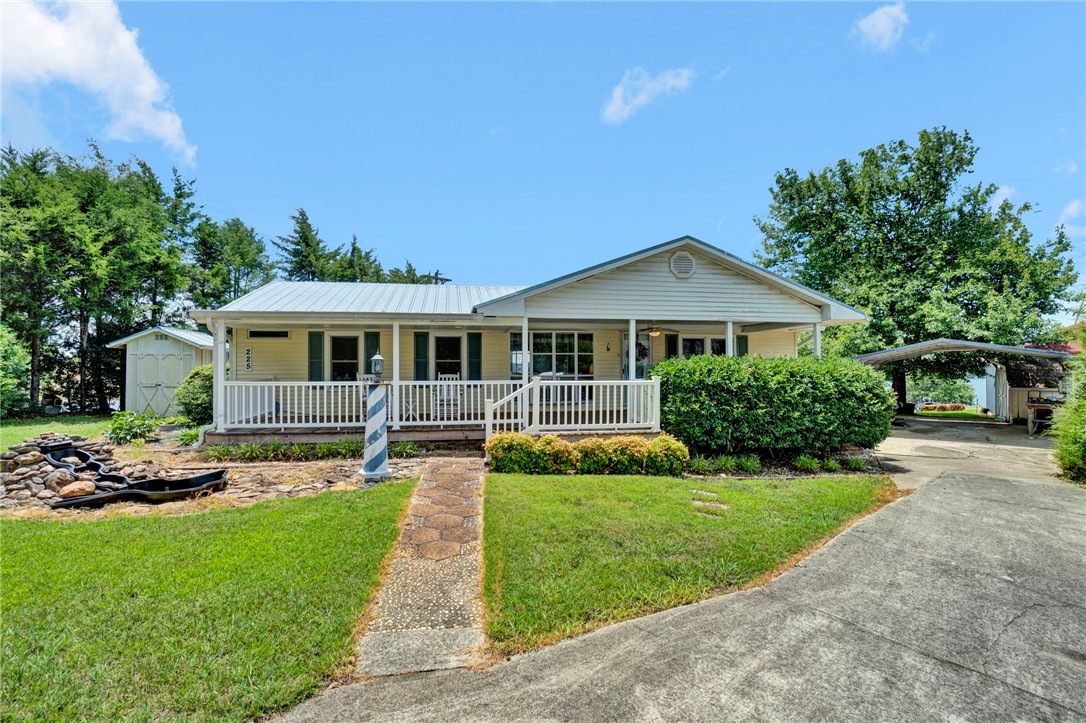 225 Nicholson Cove Road Seneca, SC 29672 - Photo 2 of 22 A welcoming front porch extends across this charming residence, framed by mature landscaping and a practical carport.