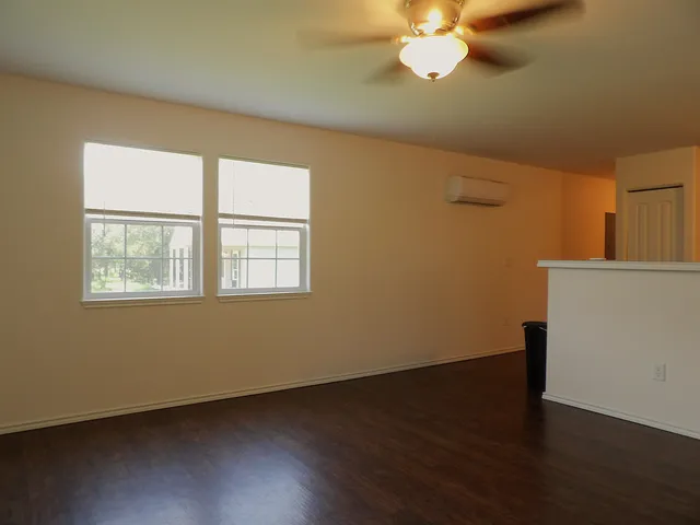 a view of a room with wooden floor and a chandelier fan