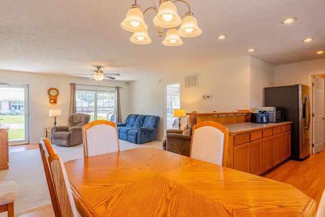 a large white kitchen with a stove a refrigerator a dining table and chairs with wooden floor