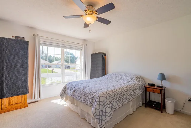 a bedroom with a bed a dresser and a chandelier