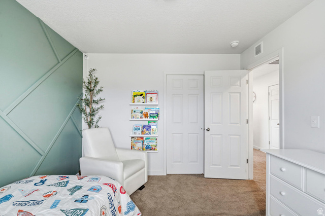 7685 Timber Country Road Eagle Mountain, UT 84005 - Photo 20 of 39 Bedroom featuring a decorative accent wall, white interior doors, and neutral carpeting