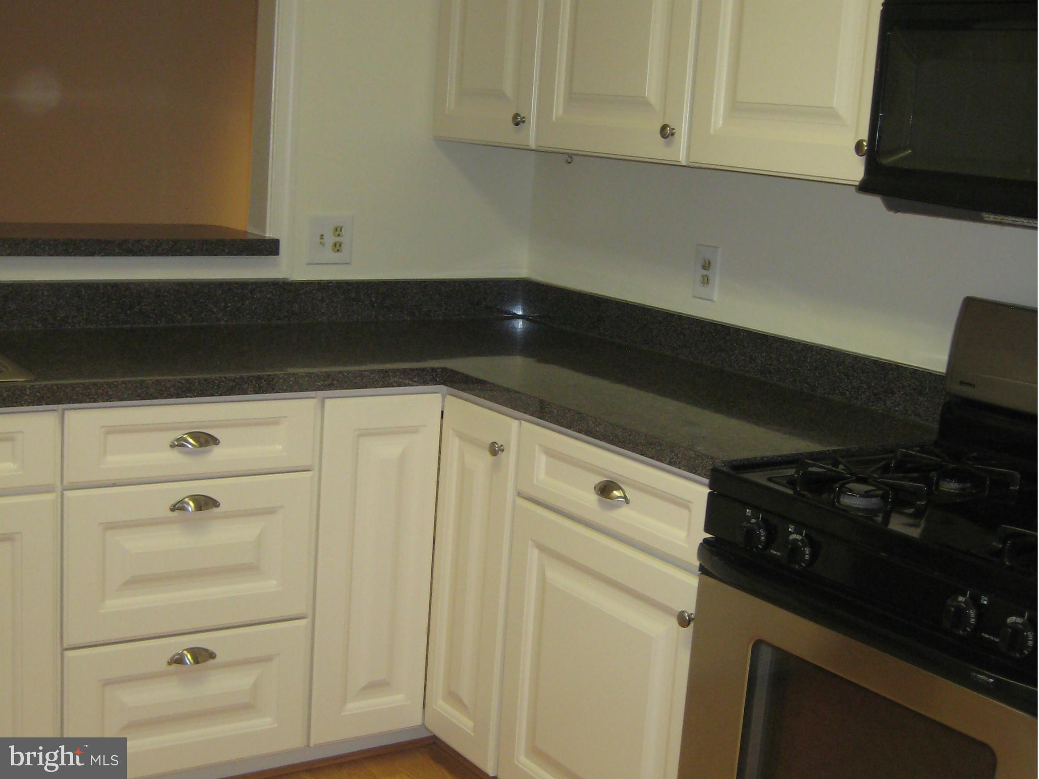 2226 Hunter's Run Drive, Unit 2226 Reston, VA 20191 - Photo 11 of 26 a kitchen with white cabinets and black appliances