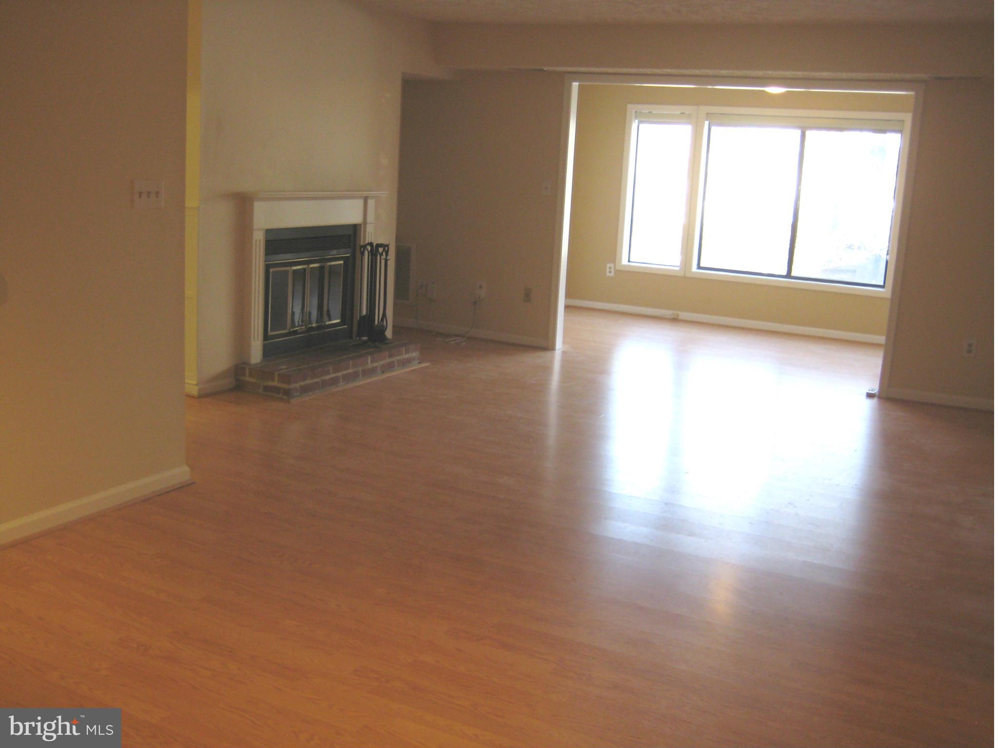 2226 Hunter's Run Drive, Unit 2226 Reston, VA 20191 - Photo 3 of 26 an empty room with wooden floor fireplace and windows
