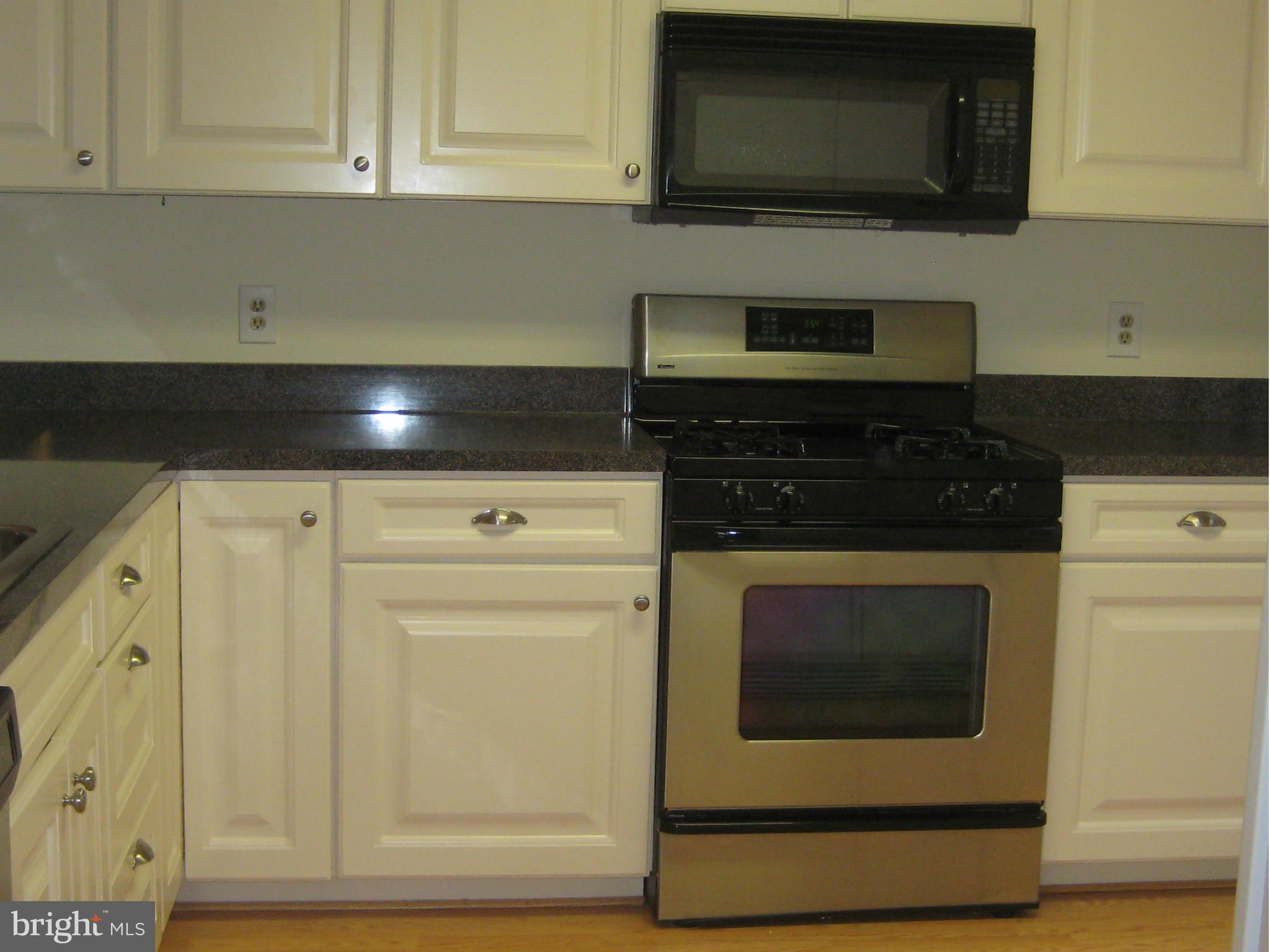 2226 Hunter's Run Drive, Unit 2226 Reston, VA 20191 - Photo 9 of 26 a kitchen with stainless steel appliances granite countertop a stove a microwave and a white cabinets