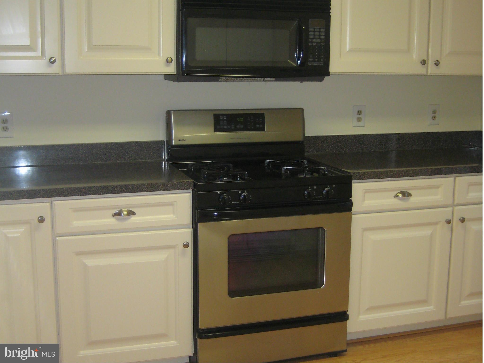 2226 Hunter's Run Drive, Unit 2226 Reston, VA 20191 - Photo 10 of 26 a kitchen with granite countertop white cabinets and black appliances