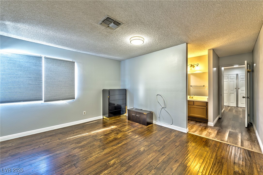 640 Whispering Palms Drive Las Vegas, NV 89123 - Photo 12 of 16 Unfurnished bedroom featuring a textured ceiling, dark wood-type flooring, and ensuite bathroom