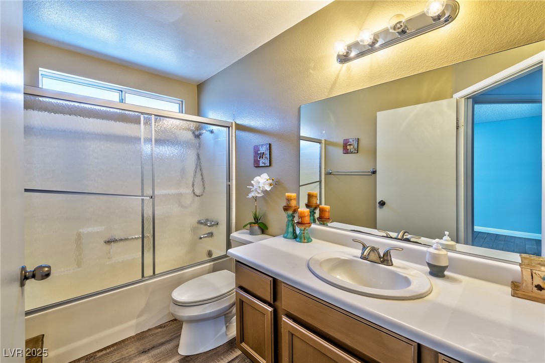 640 Whispering Palms Drive Las Vegas, NV 89123 - Photo 8 of 16 Full bath with vanity, dark wood finished floors, bath / shower combo with glass door, a textured ceiling, and a textured wall