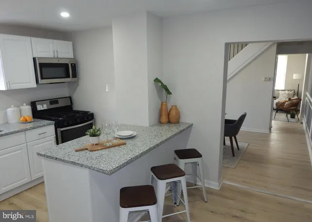 a kitchen with stainless steel appliances granite countertop a stove top oven a dining table and chairs with wooden floor