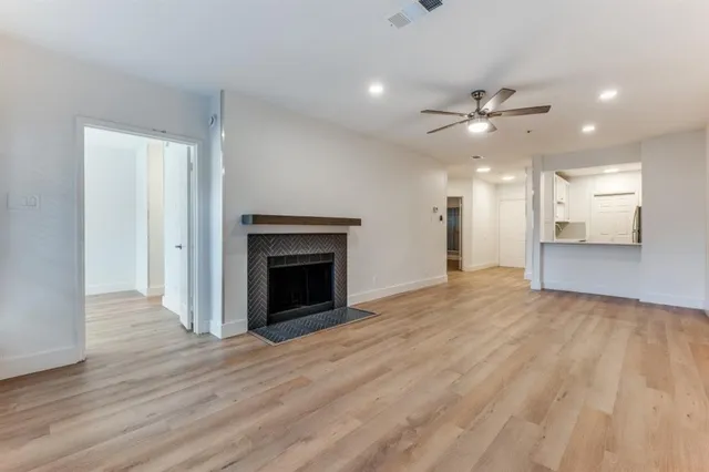 a view of a livingroom with a fireplace a ceiling fan and wooden floor