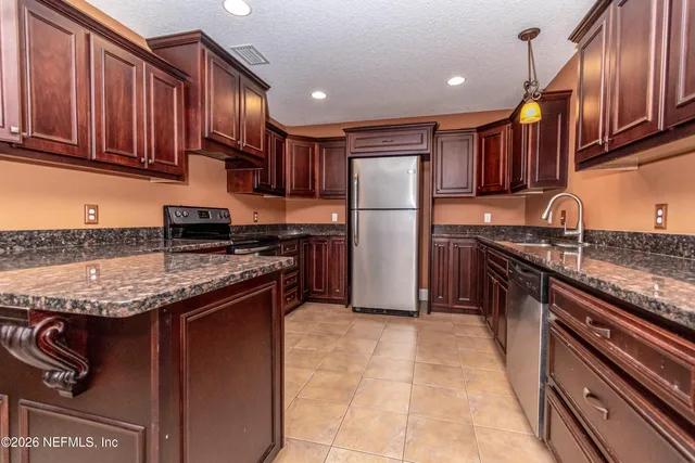 a open kitchen with stainless steel appliances granite countertop a stove kitchen island a refrigerator and a sink