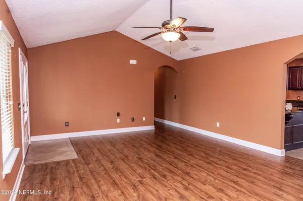 a view of an empty room with wooden floor and a window
