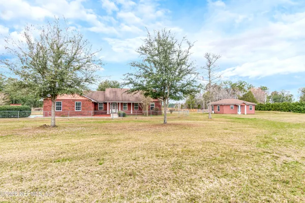 a view of a house with a big yard and large trees