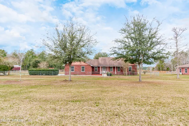 a view of a house with a big yard and large trees