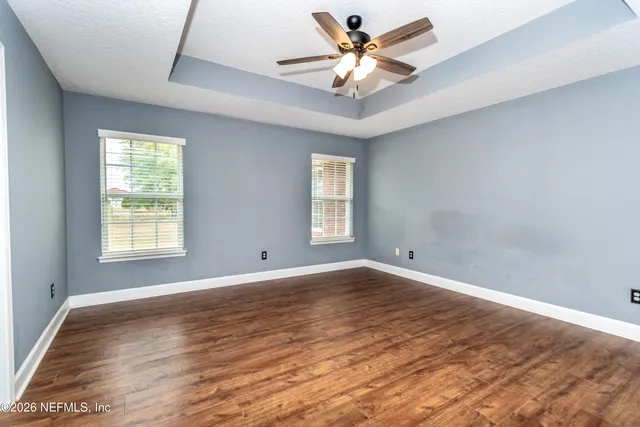 an empty room with wooden floor and a ceiling fan