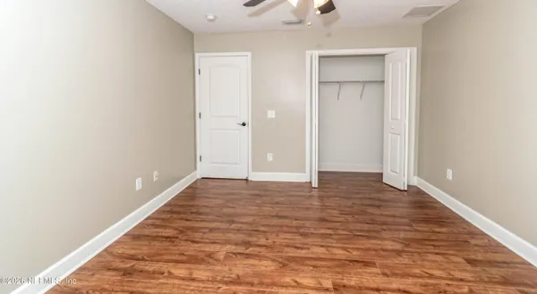 an empty room with wooden floor chandelier fan and windows