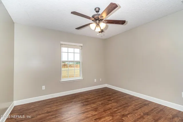 an empty room with wooden floor closet and windows