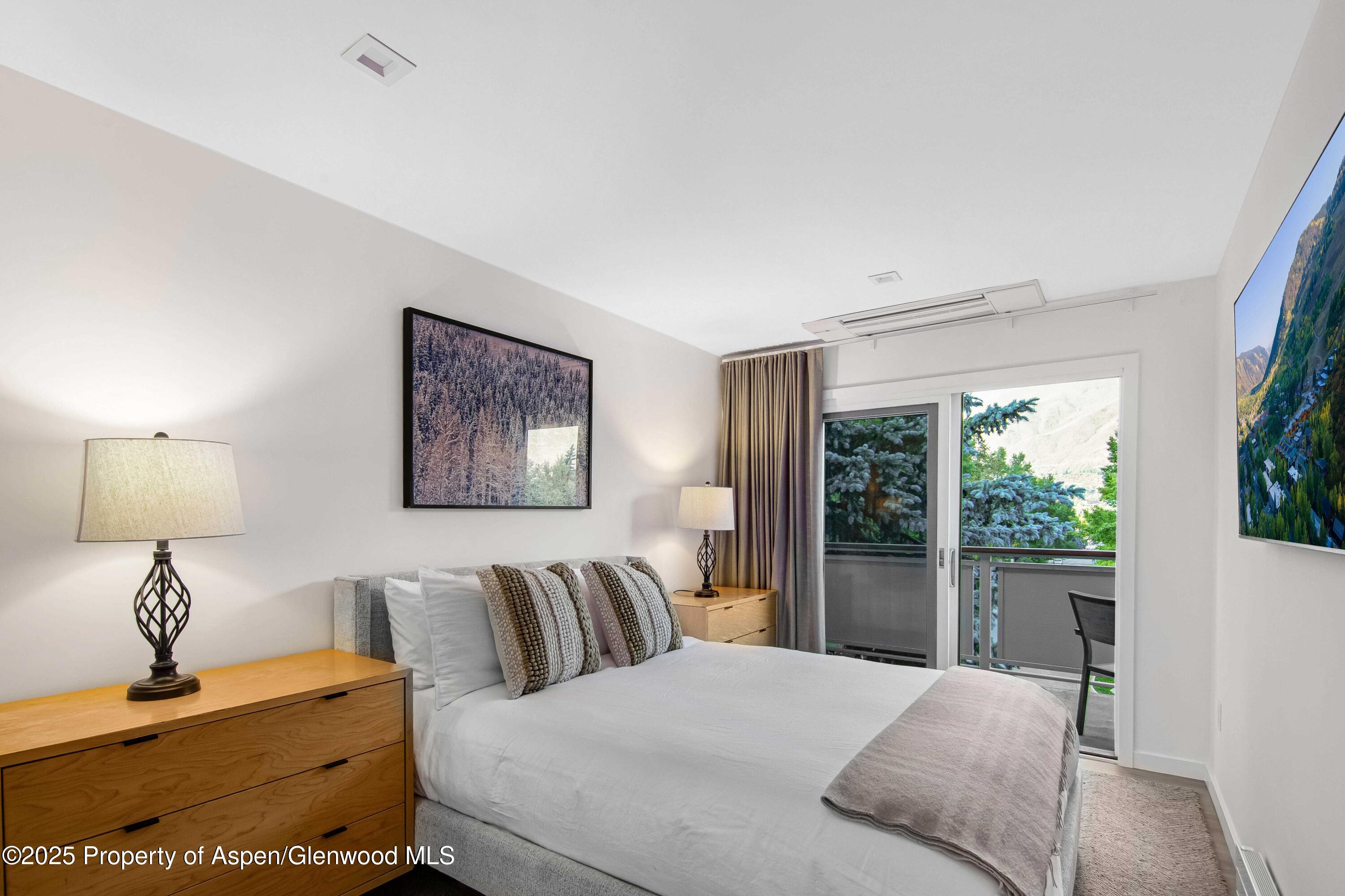 100 East Dean Street, Unit 3B Aspen, CO 81611 - Photo 11 of 16 a bedroom with a balcony a bed and a lamp on table