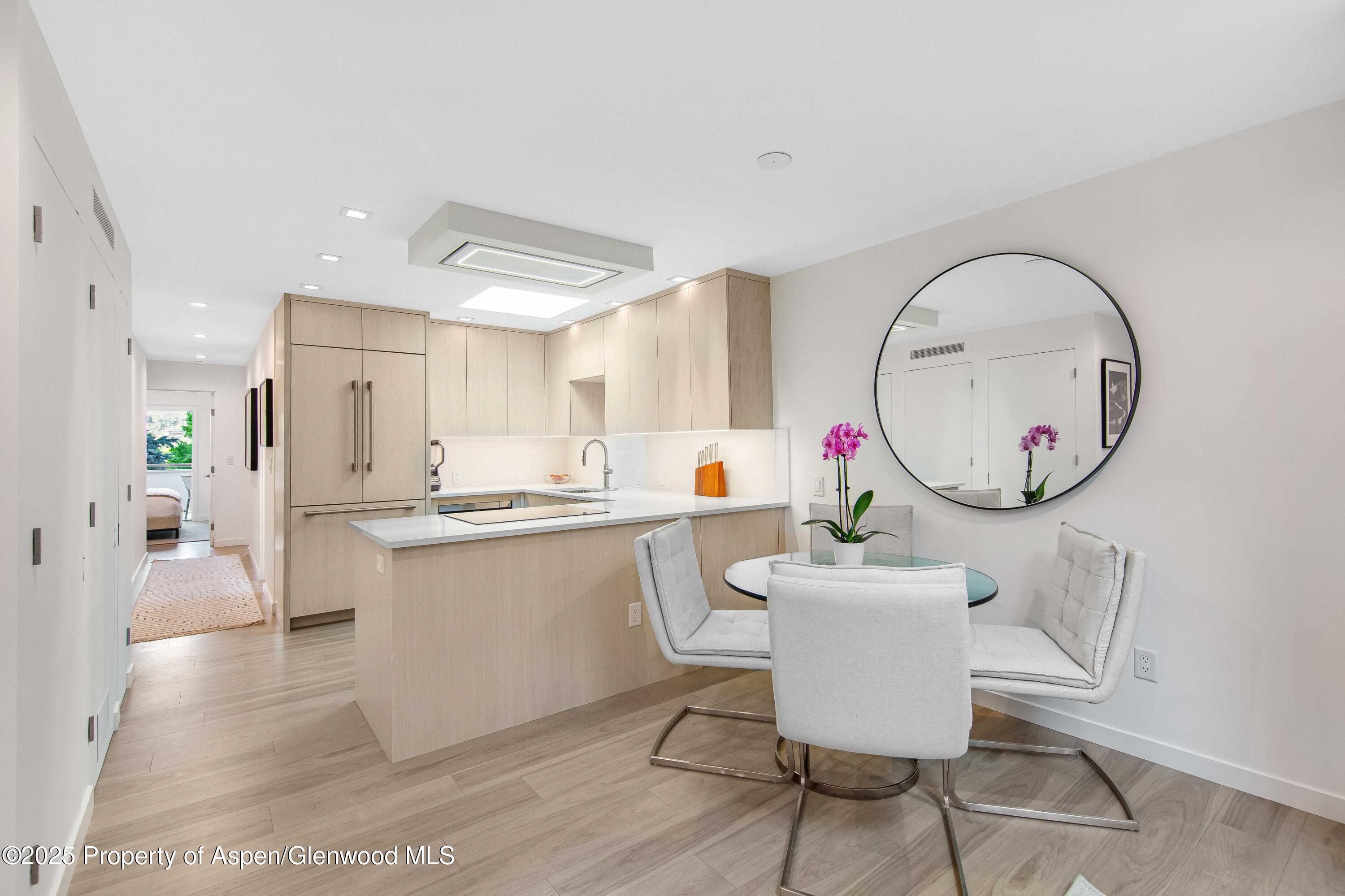 100 East Dean Street, Unit 3B Aspen, CO 81611 - Photo 3 of 16 a kitchen with a dining table chairs and white cabinets