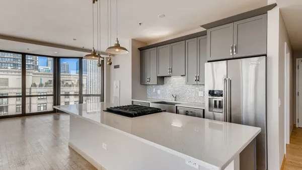 a large kitchen with stainless steel appliances a large window a oven a refrigerator a sink and a stove