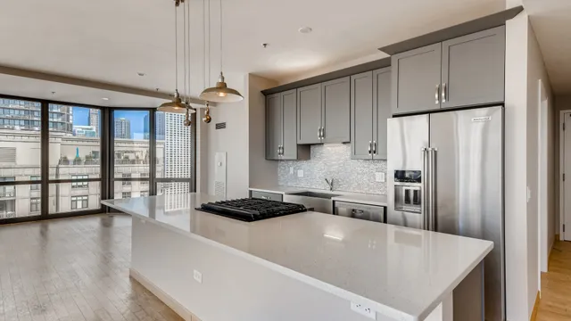 a large kitchen with stainless steel appliances a large window a oven a refrigerator a sink and a stove