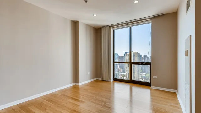 a view of an empty room with wooden floor and closet