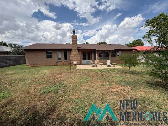 1037 Oakhurst Road Clovis, NM 88101 - Photo 20 of 21 Brick exterior featuring a central stone chimney, a paved patio area, and an expansive lawn