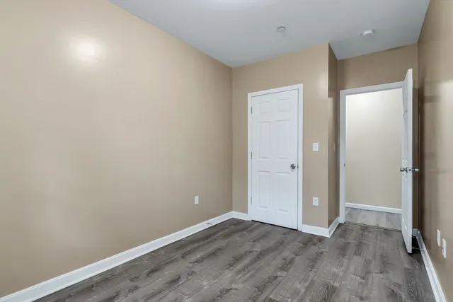 a view of an empty room with wooden floor and closet