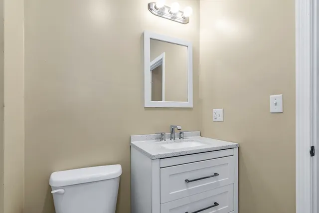 a bathroom with a toilet sink vanity and mirror