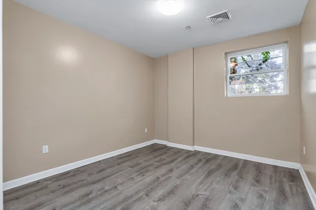 an empty room with wooden floor and window