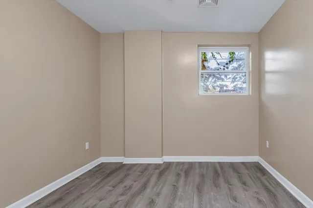 a view of an empty room with wooden floor and window