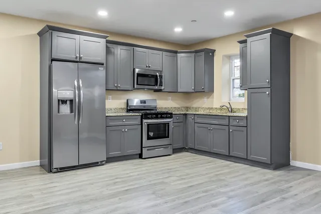 a kitchen with stainless steel appliances granite countertop a refrigerator and a stove top oven