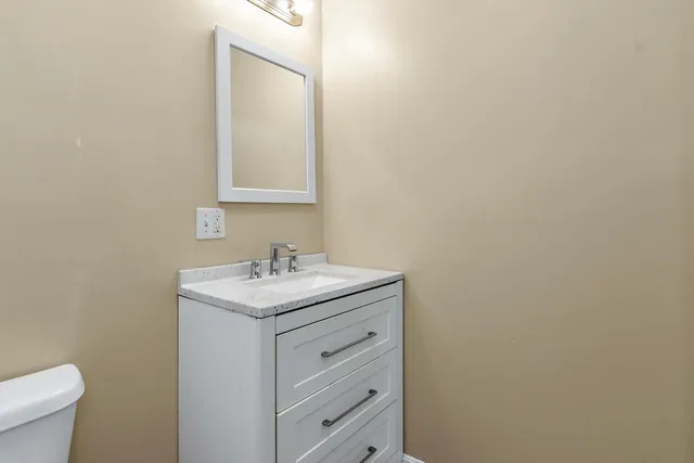 a bathroom with a granite countertop sink and a toilet