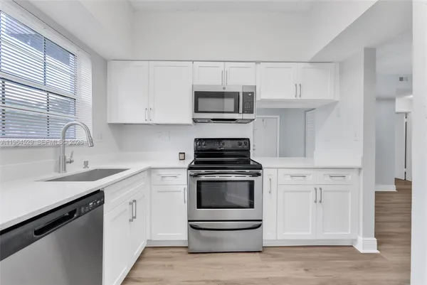 a kitchen with white cabinets and appliances