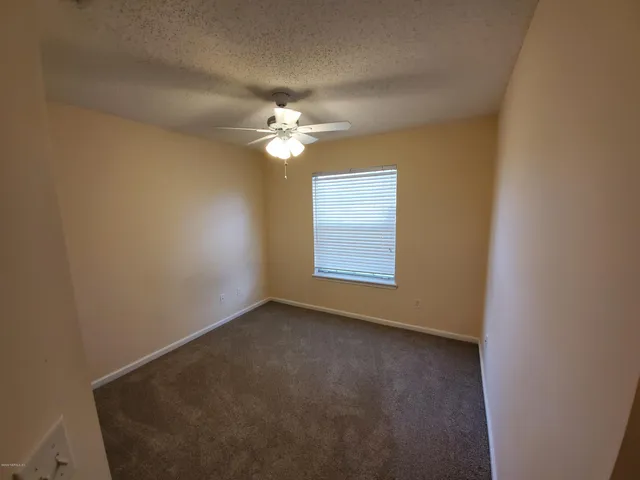 an empty room with closet and a ceiling fan