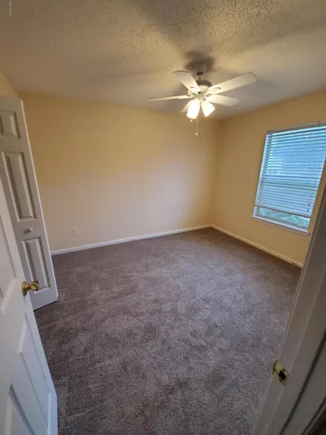an empty room with closet and a chandelier fan