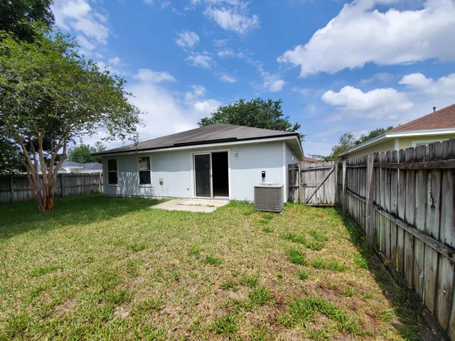 a backyard of a house with plants and large tree