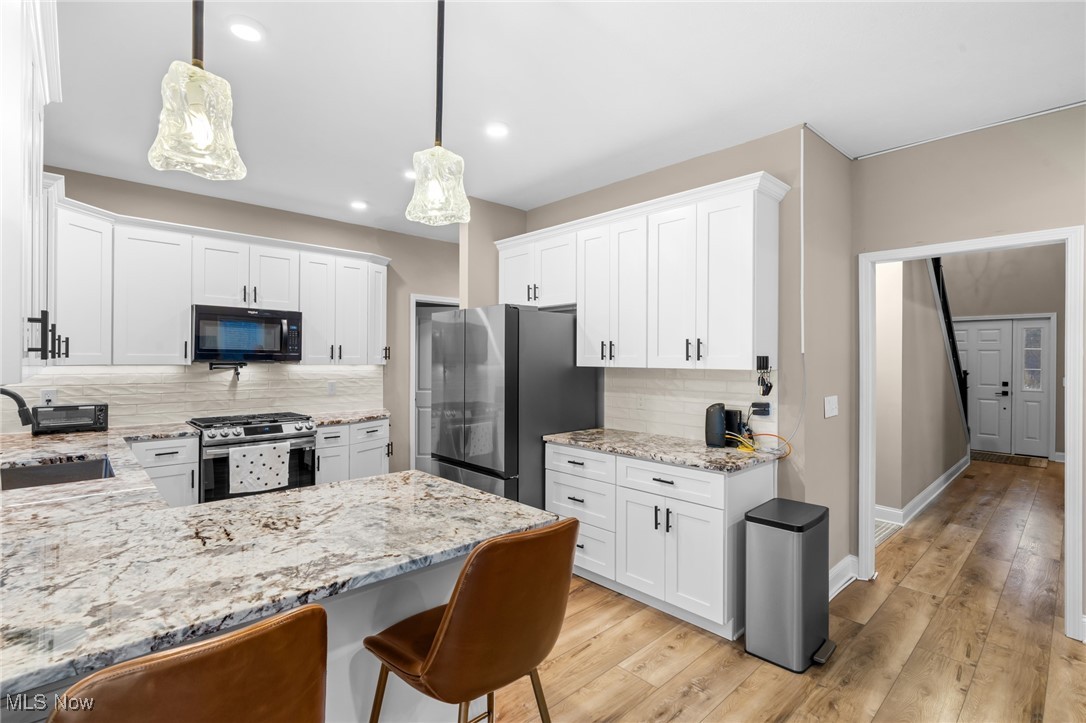 39600 Aurora Road Solon, OH 44139 - Photo 13 of 49 Kitchen featuring light stone counters, appliances with stainless steel finishes, white cabinets, and a peninsula