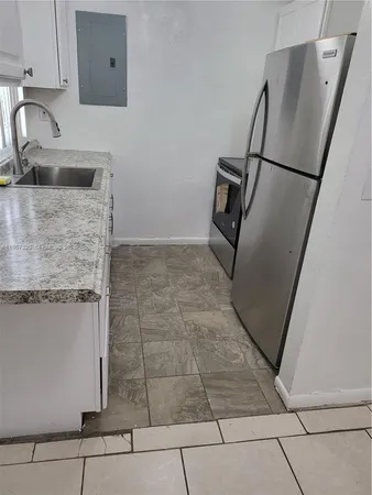 a kitchen with granite countertop a refrigerator and a sink