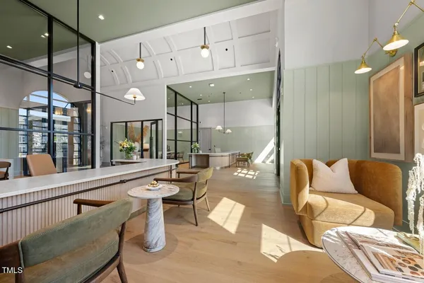 a living room with stainless steel appliances furniture a rug and a kitchen view