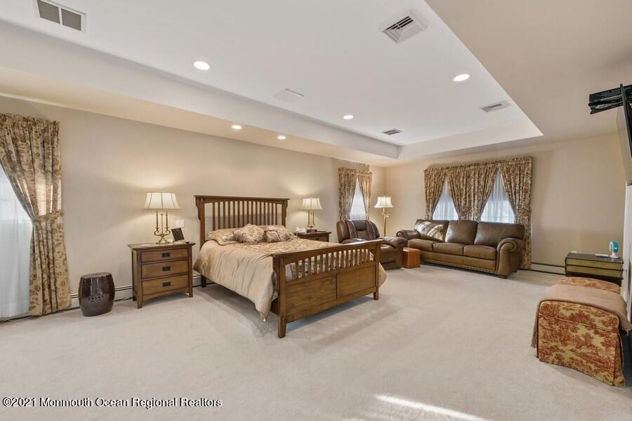 179 Stone Hill Road Colts Neck, NJ 07722 - Photo 32 of 57 a spacious bedroom with a bed a couch and a dresser with wooden floor